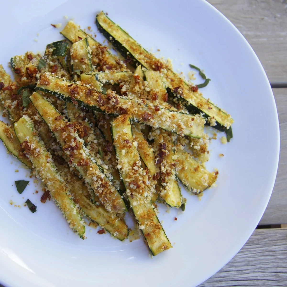 Freshly made Parmesan zucchini fries, ready to dip in a cool, herby dipping sauce.