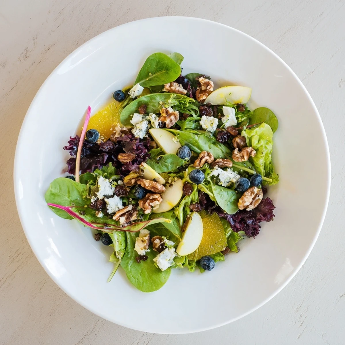 A heaping bowl of Seasonal Cranberry and Walnut Salad, tossed and dressed in a tangy orange vinaigrette.
