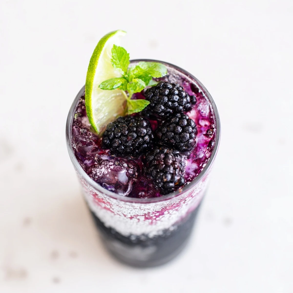 A layered Dark Matter Mocktail, a visually stunning black drink with blackberry syrup and citrus.