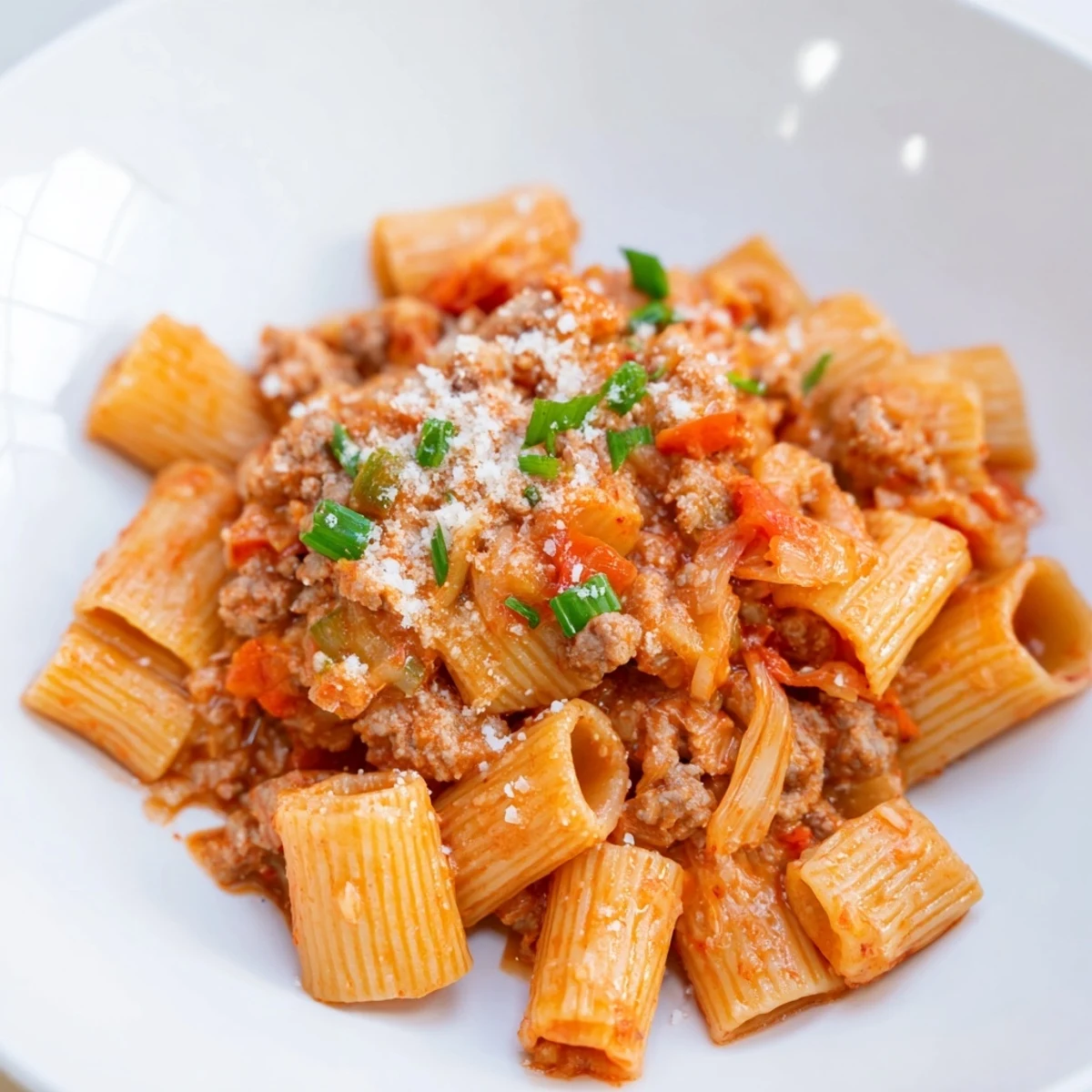 Steaming Chaos Cooking Kimchi Ragu Pasta, with creamy sauce and scallions sprinkled on top.