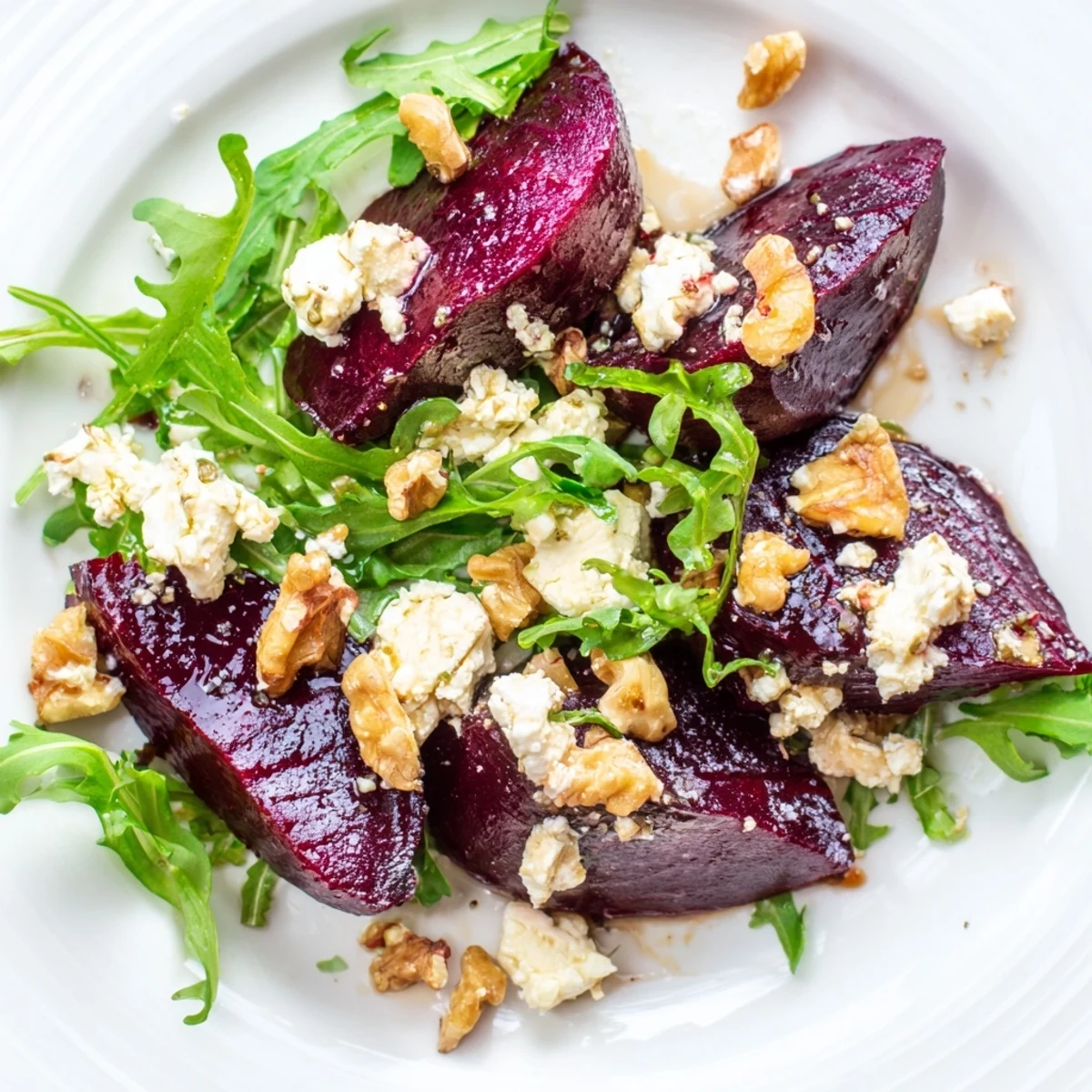 Crisp toasted walnuts and a bright balsamic vinaigrette garnish the vibrant red and green Roasted Beet Goat Cheese Salad in a rustic ceramic bowl.