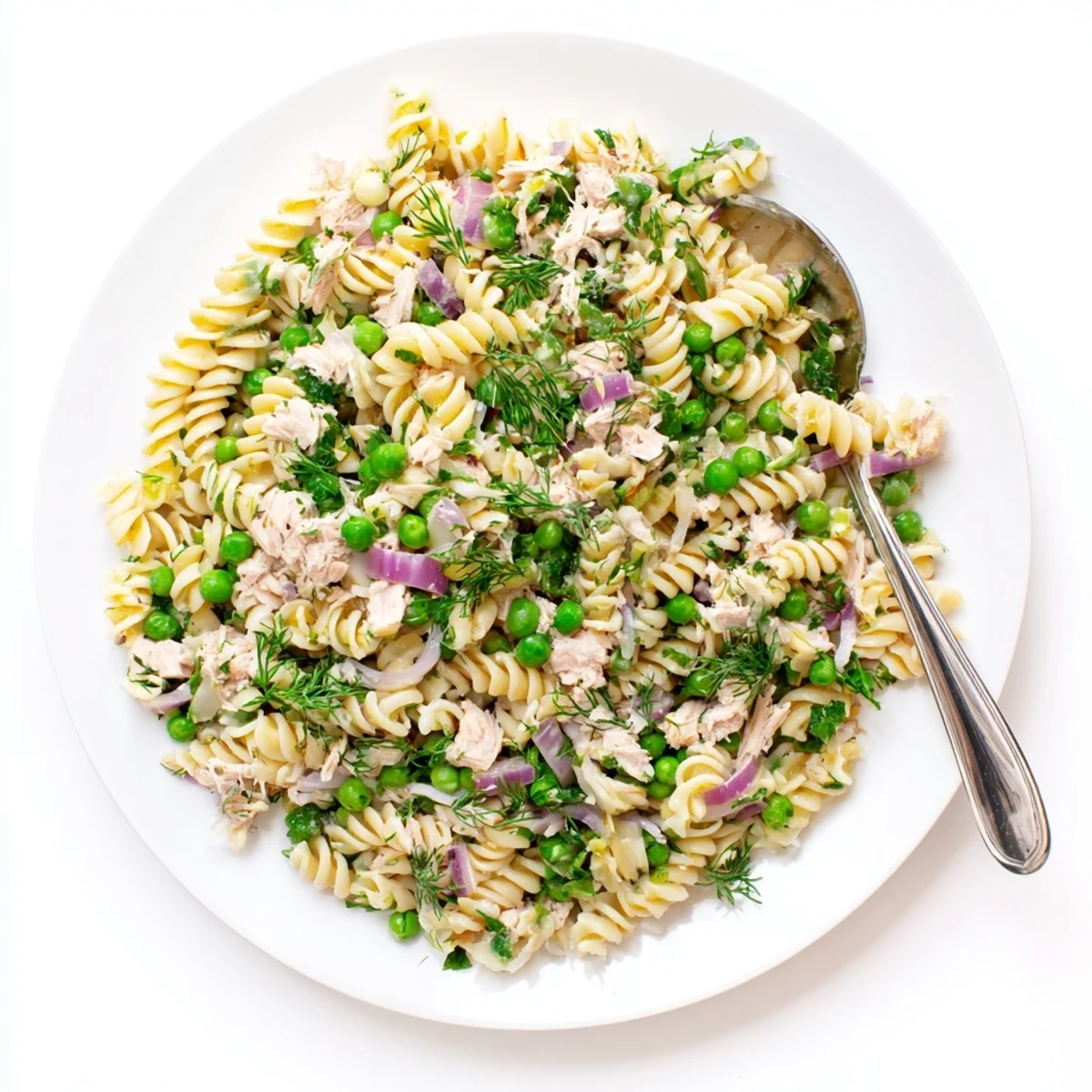 A vibrant bowl of Lemony Tuna Pasta Salad, featuring flaked tuna, bright green peas, and fresh dill mixed with fusilli.