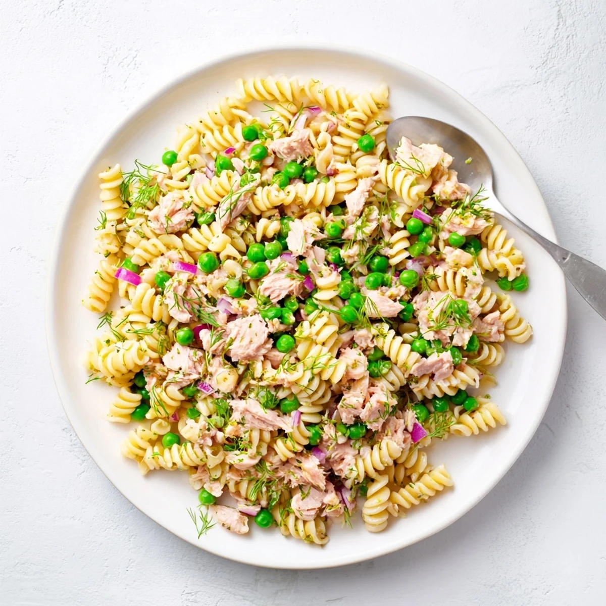 Bright yellow lemon slices and fresh herbs garnish this chilled Lemony Tuna Pasta Salad, perfect for a refreshing summer lunch.