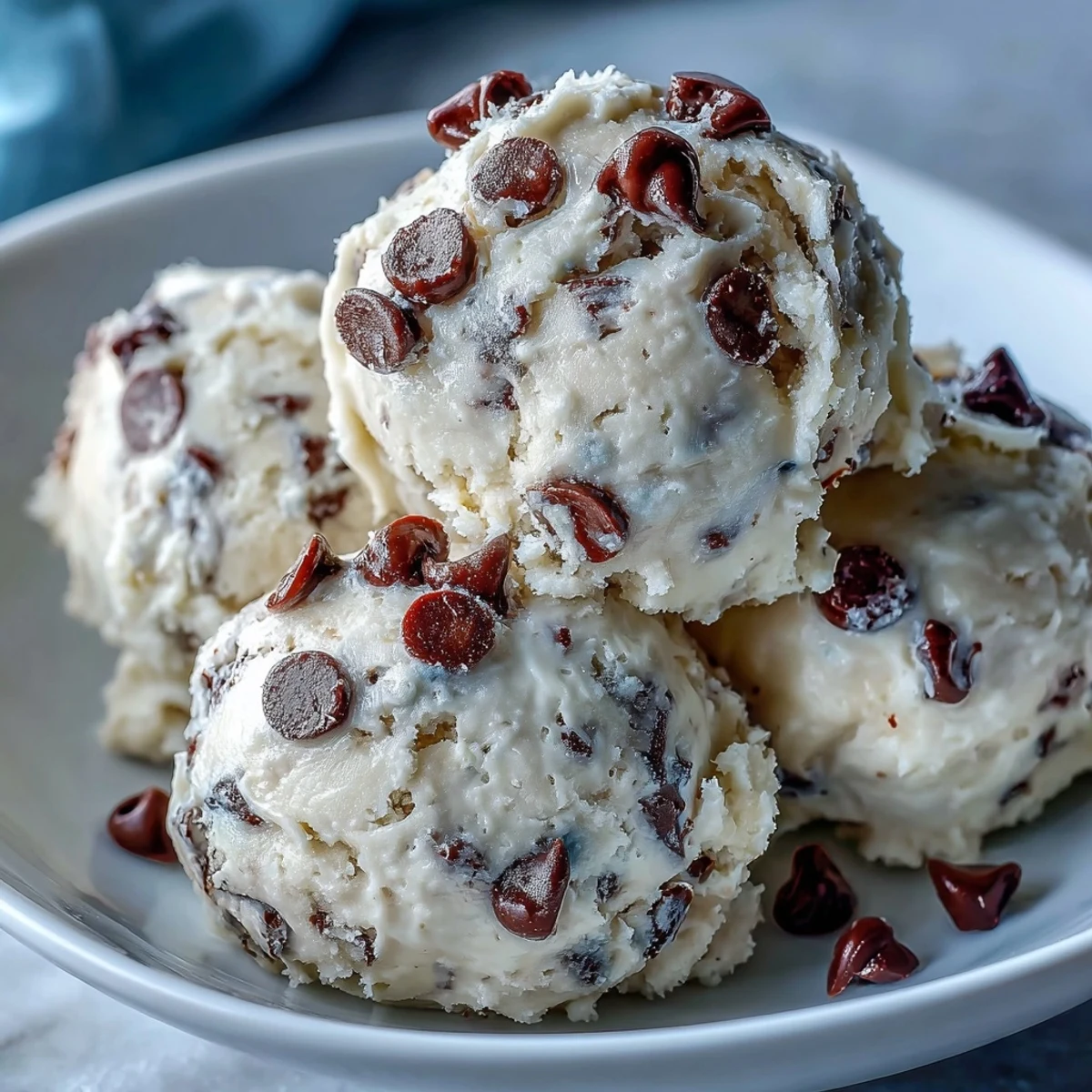Freshly chilled Greek Yogurt Cookie Dough in a bowl with mini chocolate chips and a wooden scoop.