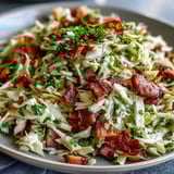 Colorful bowl of German Cabbage Coleslaw with Shredded Ham topped with fresh parsley, ready to serve as a hearty side. 