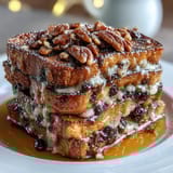 A close-up shot of warm Mexican bread pudding, Capirotada, showing golden toasted bread soaked in syrup with melted cheese and raisins.