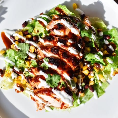 Grilled BBQ chicken slices resting on a bed of crisp romaine with charred corn and black beans.  