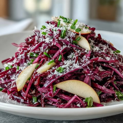 A close-up of Red Cabbage Coleslaw With Apple and Parmesan, featuring vibrant purple and green shreds and glistening vinaigrette.