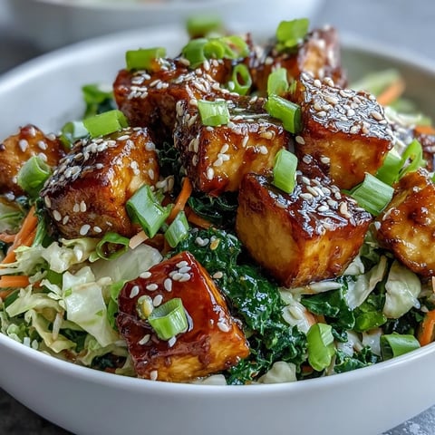 Golden pan-fried tofu cubes glisten in a hot skillet alongside vibrant sautéed cabbage, kale, and julienned carrots for this Tofu Egg Roll in a Bowl.