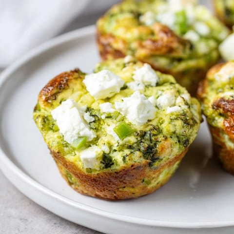 A close-up of fluffy Savory Zucchini and Feta Muffins, showcasing the feta crumbles and herbs.