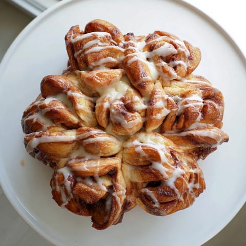 Enjoy a warm slice of this soft, frosted Cinnamon Roll Pull-Apart Snowflake, perfect for sharing.
