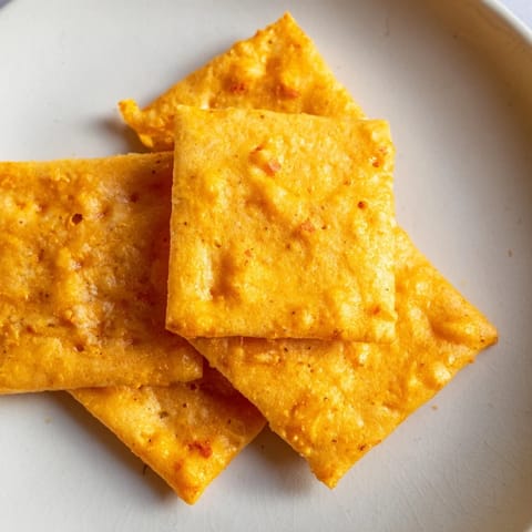 A close-up view of freshly baked Crispy Cheeto Cheese Crackers, highlighting their jagged edges and savory cheese coating.  