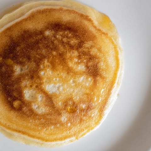 Stack of fluffy, golden brown banana pancakes topped with sliced bananas and a drizzle of maple syrup.  