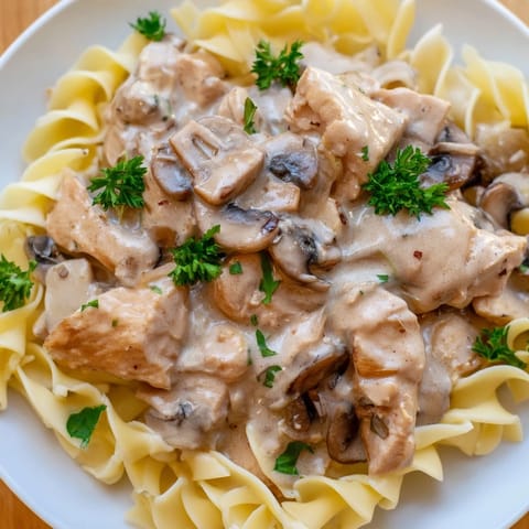 A close-up of Chicken and Mushroom Stroganoff shows a rich, velvety sauce coating buttery noodles, garnished with fresh parsley for a comforting weeknight dinner.