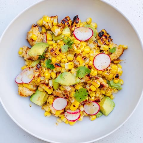 A close-up of Roasted Corn & Chicken Chopped Salad featuring juicy chicken, creamy avocado, and smoky corn on a bed of romaine.