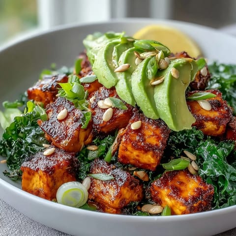 Golden tofu cubes and sautéed kale fill a white ceramic bowl, topped with creamy avocado slices and a lemon wedge for this Tofu Breakfast Bowl.  