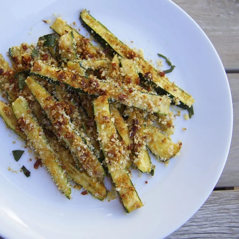 Freshly made Parmesan zucchini fries, ready to dip in a cool, herby dipping sauce.