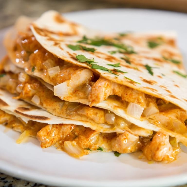 Golden-brown wedges of a Butter Chicken Quesadilla with fresh cilantro, a flavorful fusion dish.