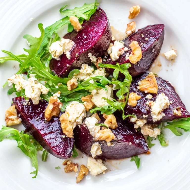 Crisp toasted walnuts and a bright balsamic vinaigrette garnish the vibrant red and green Roasted Beet Goat Cheese Salad in a rustic ceramic bowl.