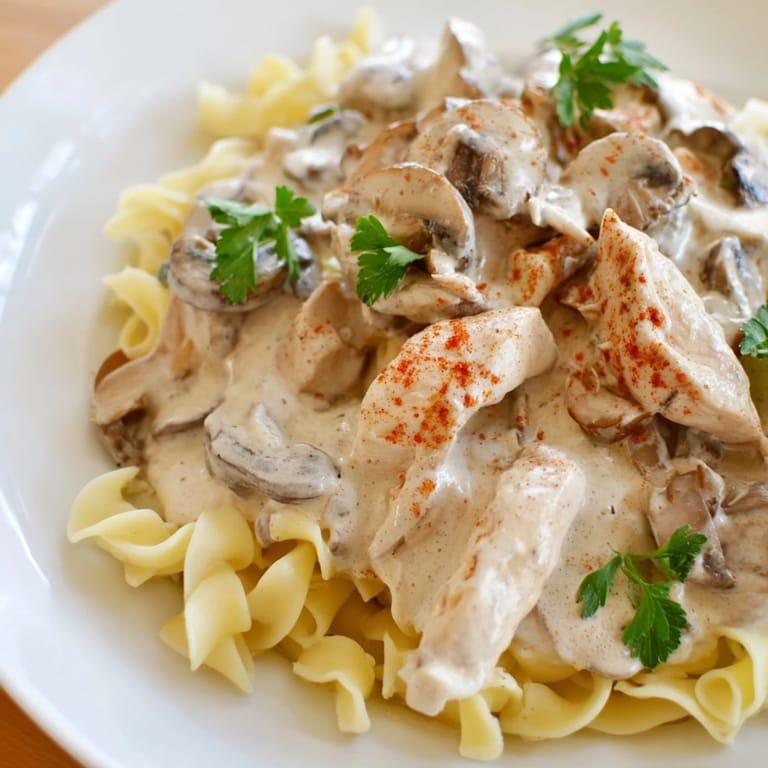 Savory Chicken and Mushroom Stroganoff in a skillet, featuring tender chicken pieces and earthy mushrooms in a luscious sauce, perfect for serving over warm egg noodles.