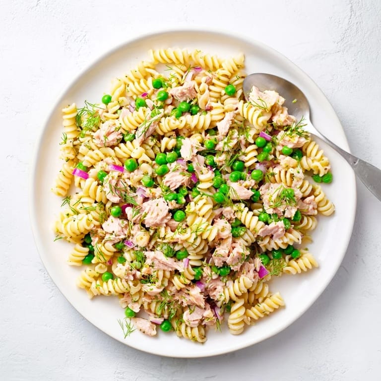 Bright yellow lemon slices and fresh herbs garnish this chilled Lemony Tuna Pasta Salad, perfect for a refreshing summer lunch.