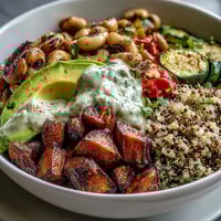 Roasted sweet potatoes and zucchini top a Black-Eyed Pea Buddha Bowl drizzled with creamy tahini dressing.